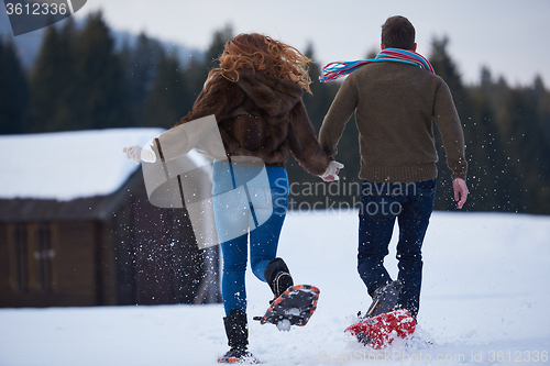Image of couple having fun and walking in snow shoes