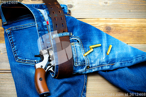 Image of revolver nagant with cartridges in old blue jeans