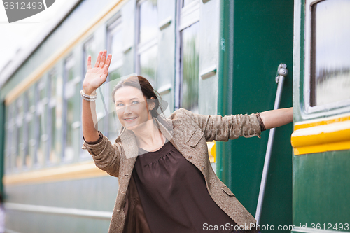 Image of smiling woman waving from the departing train