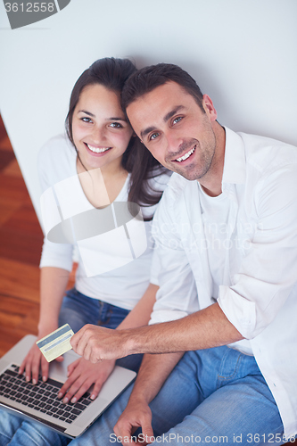 Image of relaxed young couple working on laptop computer at home