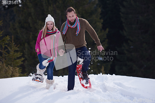 Image of couple having fun and walking in snow shoes