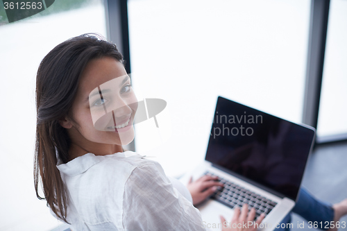 Image of relaxed young woman at home working on laptop computer