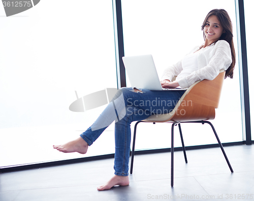 Image of relaxed young woman at home working on laptop computer