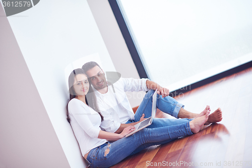 Image of relaxed young couple working on laptop computer at home