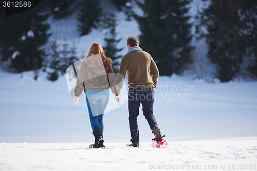 Image of couple having fun and walking in snow shoes