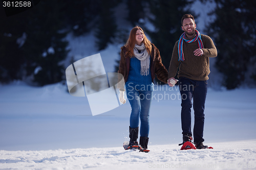 Image of couple having fun and walking in snow shoes