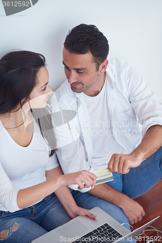 Image of relaxed young couple working on laptop computer at home