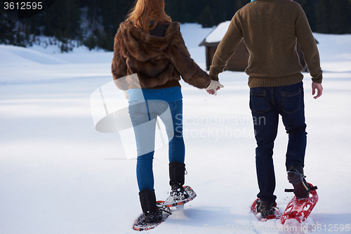 Image of couple having fun and walking in snow shoes