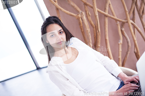 Image of relaxed young woman at home working on laptop computer