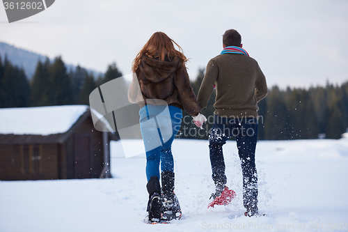 Image of couple having fun and walking in snow shoes