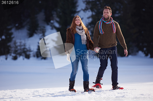 Image of couple having fun and walking in snow shoes