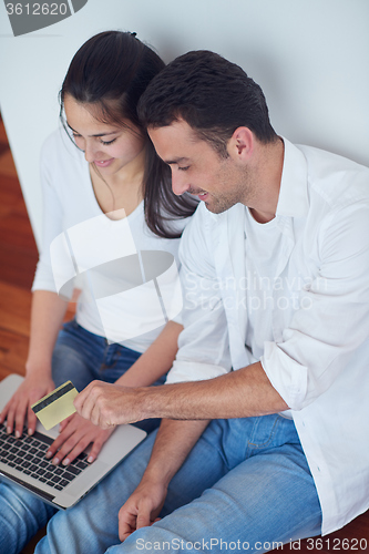 Image of relaxed young couple working on laptop computer at home