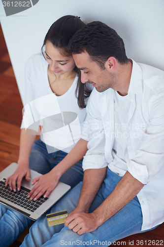 Image of relaxed young couple working on laptop computer at home