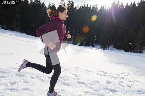 Image of yougn woman jogging outdoor on snow in forest