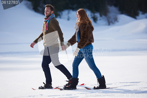 Image of couple having fun and walking in snow shoes