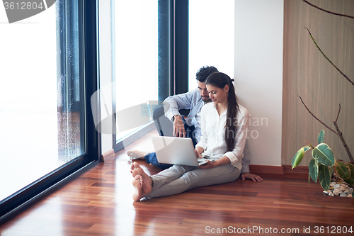 Image of relaxed young couple working on laptop computer at home