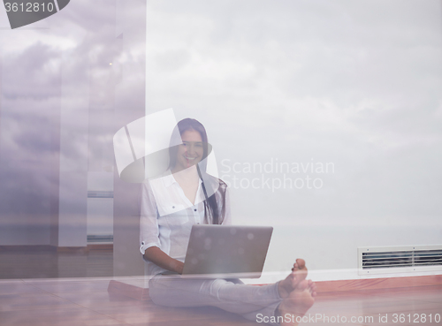 Image of relaxed young woman at home working on laptop computer