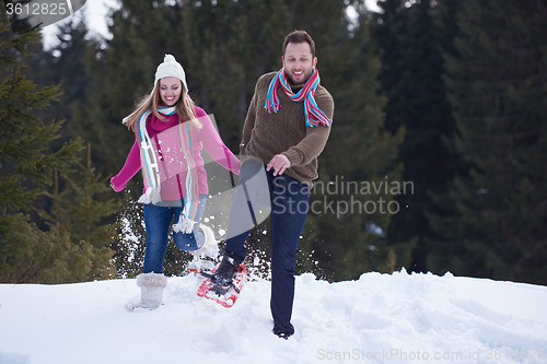 Image of couple having fun and walking in snow shoes