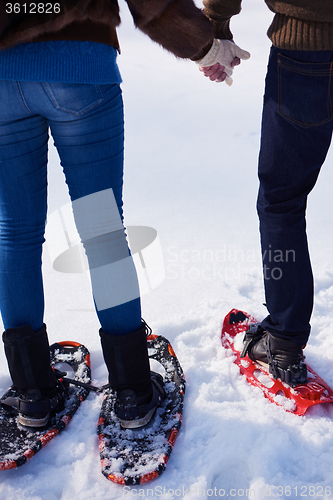 Image of couple having fun and walking in snow shoes