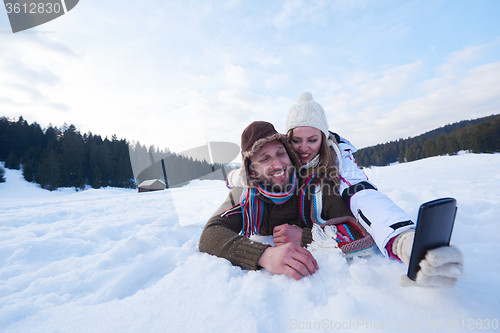 Image of romantic couple have fun in fresh snow and taking selfie