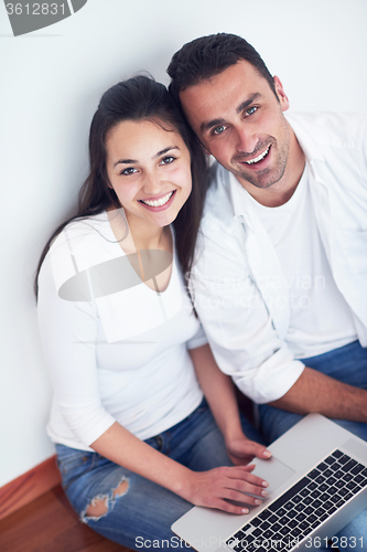 Image of relaxed young couple working on laptop computer at home