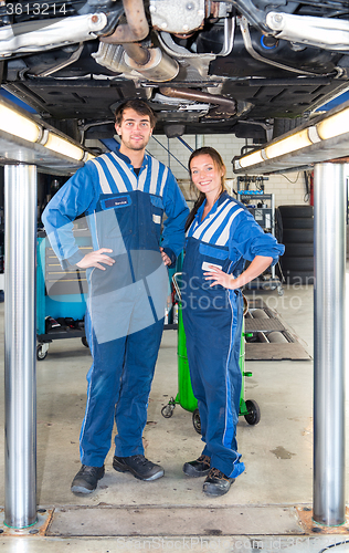 Image of Two car mechanics underneath a vehicle on a hydraulic  car lift