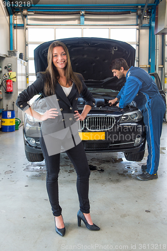 Image of Sales woman standing in front of a car, being serviced for deliv