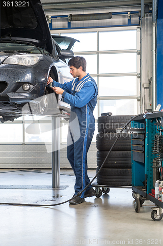 Image of Mechanic, working on a car, checking the thickness of the brake 