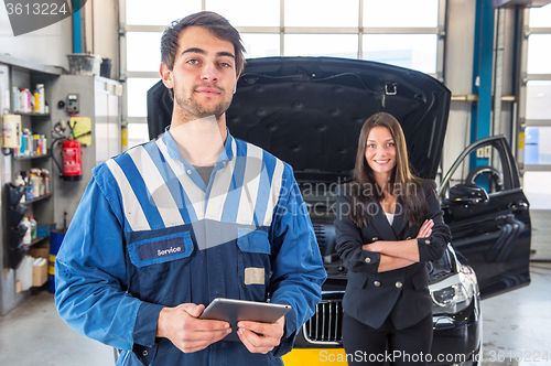 Image of Proud mechanic, posing in front of a client with her car