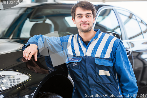 Image of Professional mechanic leaning against a car