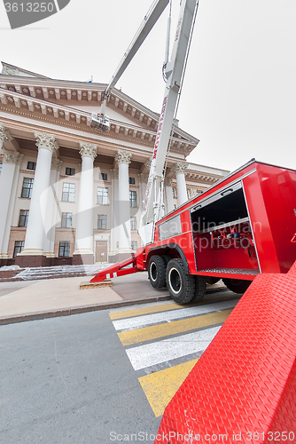 Image of Builders paint building facade by fire truck