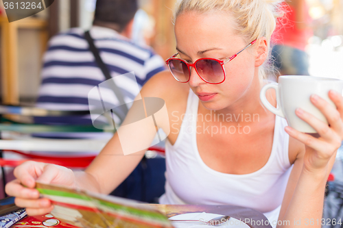 Image of Woman drinking coffee outdoor on street.