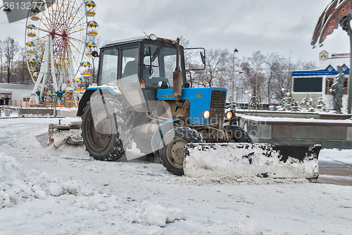 Image of Tractor with snowplowing equipment cleans street