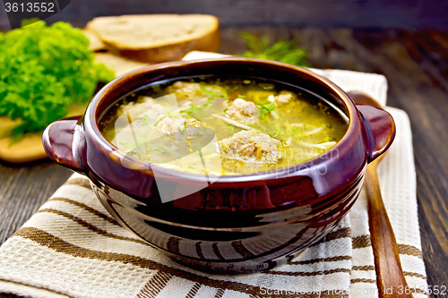 Image of Soup with meatballs and noodles in pottery on board