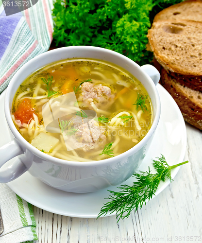 Image of Soup with meatballs and noodles in bowl on light board