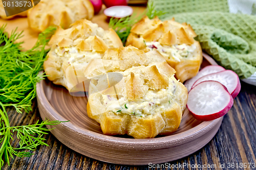 Image of Appetizer of radish and cheese in profiteroles on clay plate