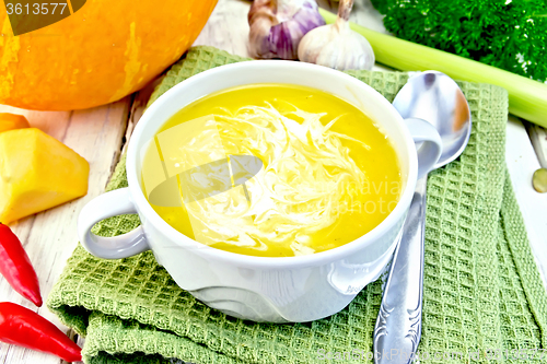 Image of Soup-puree pumpkin with cream in white bowl on green napkin