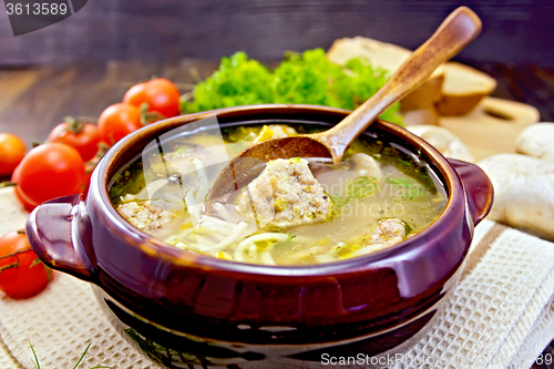 Image of Soup with meatballs and spoon in pottery on board