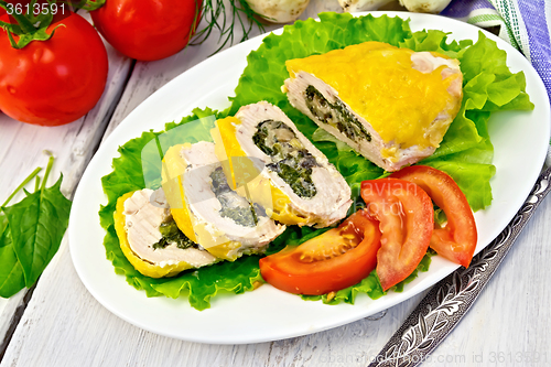 Image of Roll chicken with spinach and tomatoes on light board