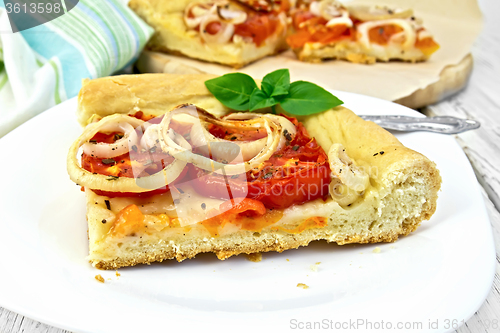 Image of Pie with onions and tomatoes in white plate on light board