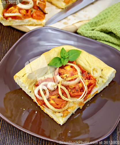 Image of Pie with onions and tomatoes in brown plate on board