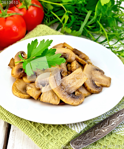 Image of Champignons fried in plate with fork on light board