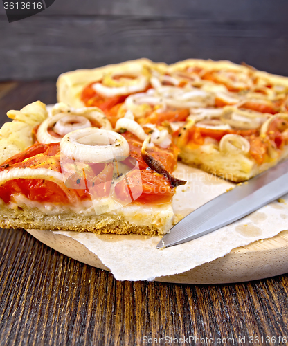 Image of Pie with onions and tomatoes on paper with knife