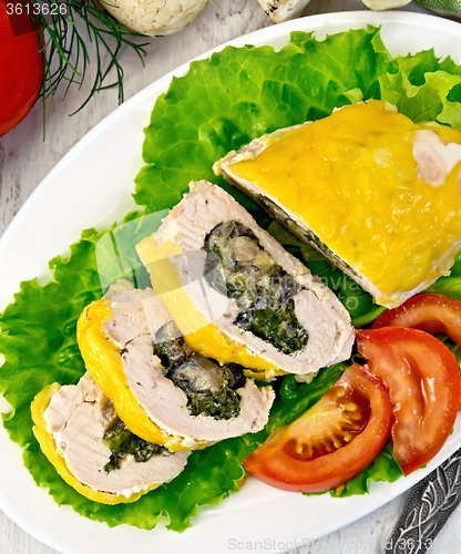 Image of Roll chicken with spinach and tomatoes on board