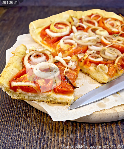 Image of Pie with onions and tomatoes on parchment and board