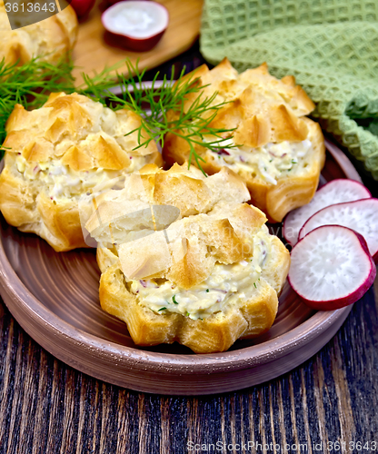 Image of Appetizer of radish and cheese in profiteroles on clay plate wit