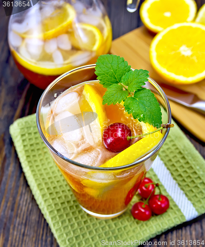 Image of Lemonade with cherry in glassful and pitcher on board