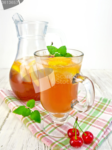 Image of Lemonade with cherry in wineglass and pitcher on board