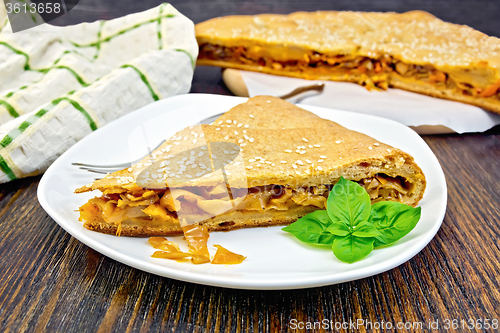 Image of Pie with cabbage and sesame in plate on board with cloth