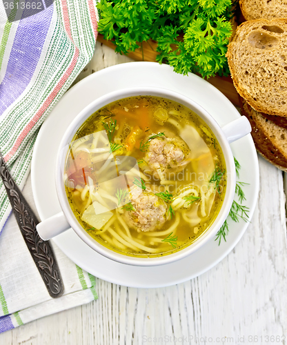 Image of Soup with meatballs and noodles in bowl on board top